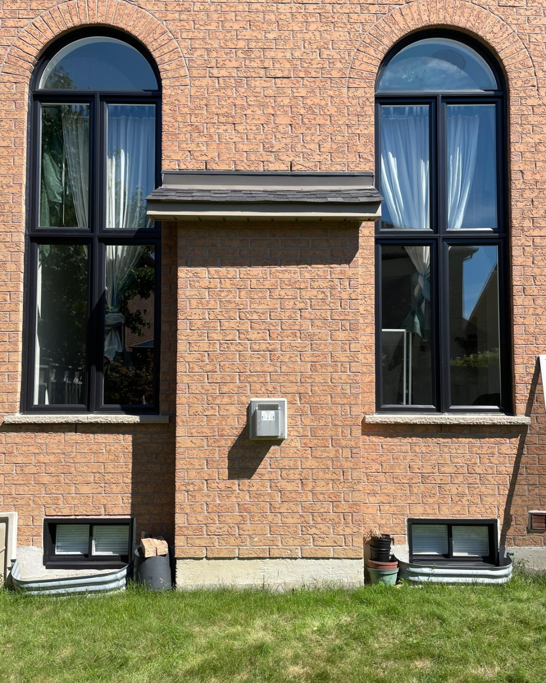Black framed arched windows on brick exterior façade