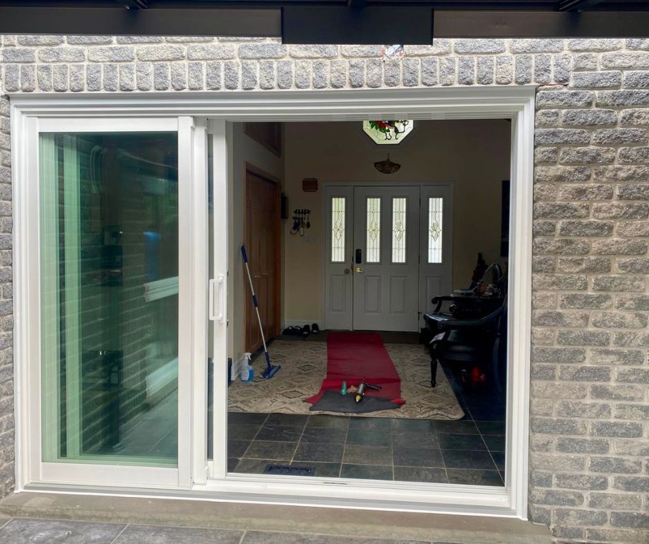 After photo of white Rimini sliding patio door in a brick wall, opening from the hallway to a covered patio