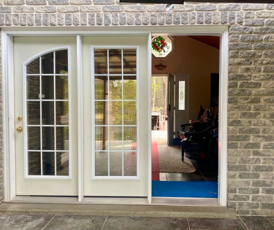 Before photo showing cream garden doors with grids and sidelite leading from the hallway to the patio