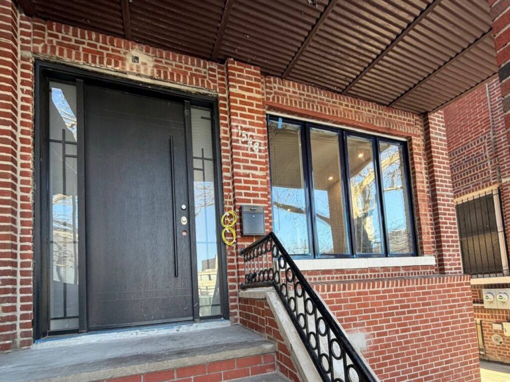 Custom entry door with sidelites on a Brooklyn brick home with slab door and wrought iron glass inserts.