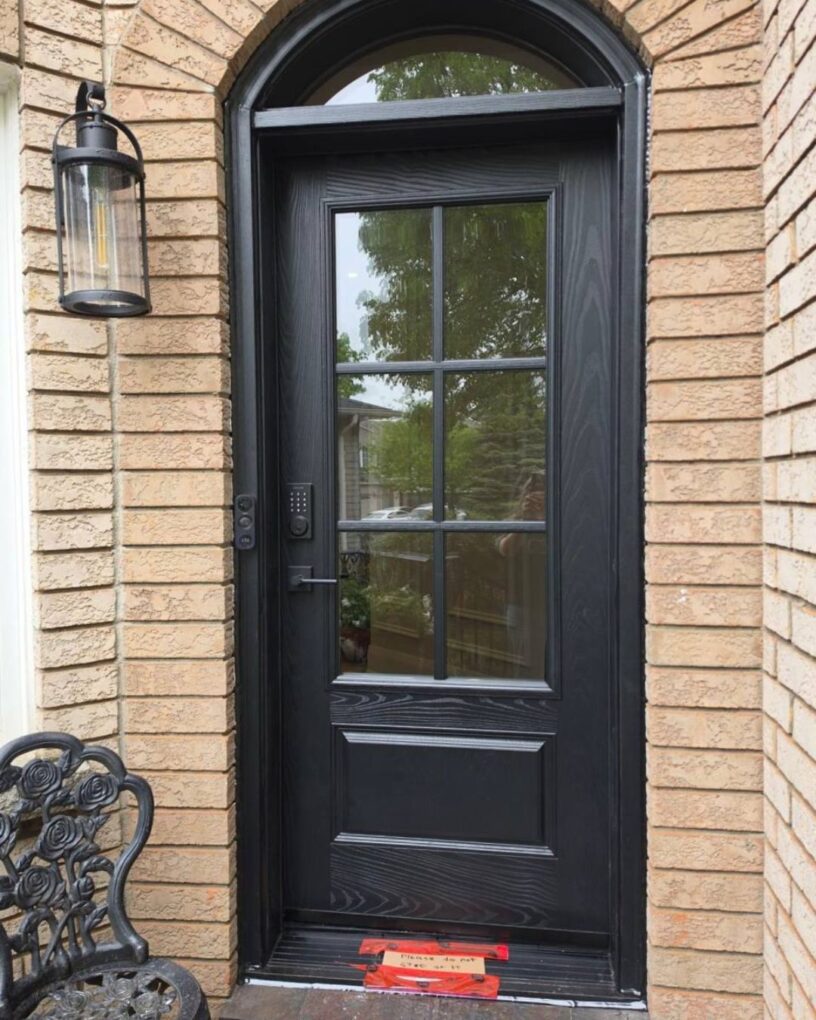 Modern black fiberglass front door installed on a brick home