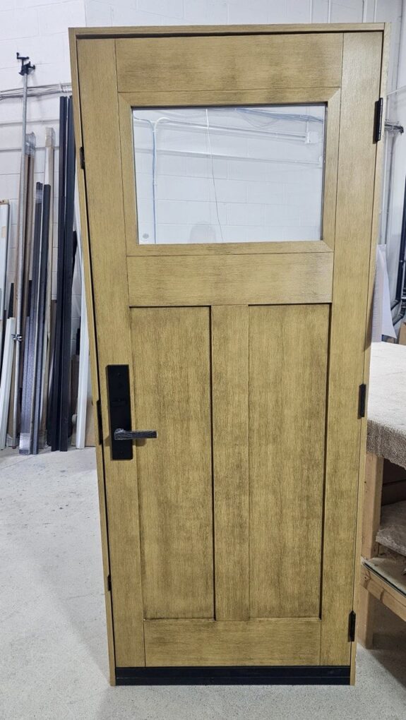 Wood grain fiberglass entry door with black hardware and multi-point lock
