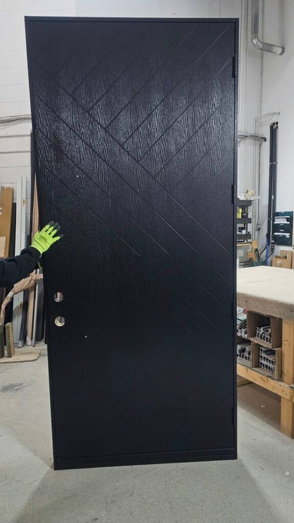 Black fiberglass front door with geometric grooving and woodgrain texture